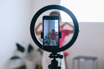 Cheerful teen girl dancing at camera filming video using phone on tripod at home, creating trendy content for social media. Young Blogger Concept. 