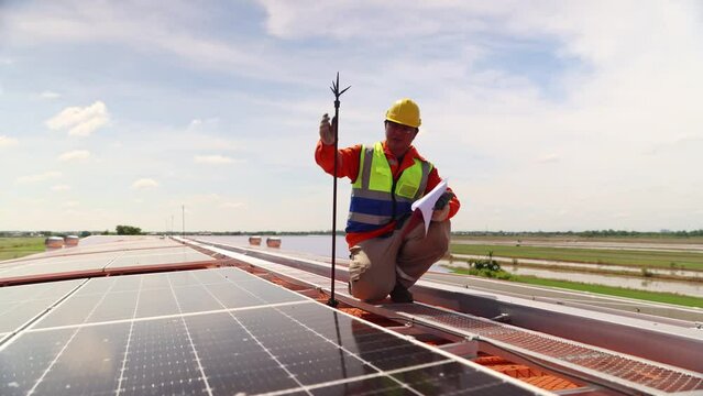 Male electrical engineer inspects and installs lightning protection equipment lightning rod on the building installs solar cell panels ground wire to the ground for safety.