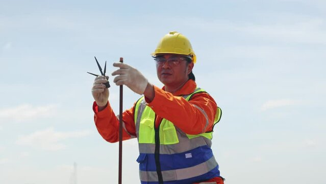 Male electrical engineer inspects and installs lightning protection equipment lightning rod on the building installs solar cell panels ground wire to the ground for safety.