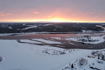 Sunset casts a fiery glow over a frozen river in Lovikka.