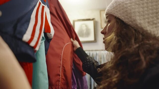 Young hipster woman shopping for clothes in vintage store or second hand shop. Female searching for fashionable retro and hip looking pieces of clothing in vintage wear or donation center 