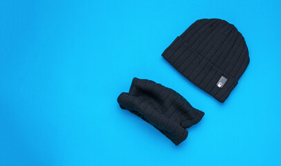 Black men's knitted hat with a scarf on a blue background.