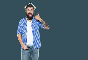 bearded man with book on head on grey background. thumb up