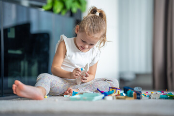 Smiling Little girl playing with small constructor toy on floor in home, educational game, spending leisure activities time concept - obrazy, fototapety, plakaty