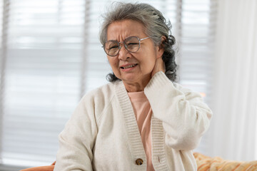 Asian Elderly senior woman with white hairs neck and shoulder pain and illness on sofa alone at home,Elderly Care and insurance Concept