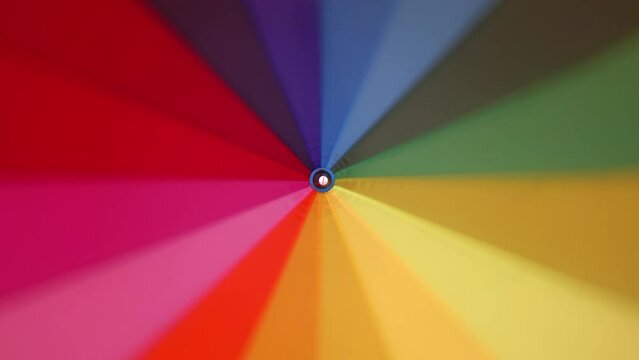 Multi-colored rainbow umbrella rotates around its axis, 4k
