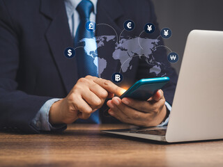 Businessman using a smartphone with a world map and currency signs for technology currency exchange and money transfer.