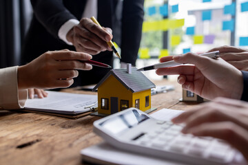 Real estate agents offer contracts to buy or rent housing. Businessman holding model small building house with property insurance at table in home sales office
 - obrazy, fototapety, plakaty