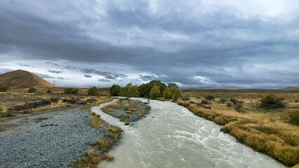 Flooded stream on the winding narrow gravel road between Lake Tekapo and Lake Pukaki in rural agricultural land