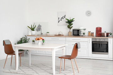 Interior of modern kitchen with pastry and houseplants on dining table