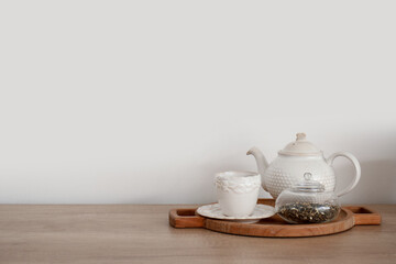 Board with teapot, cup and tea leaves on wooden kitchen counter