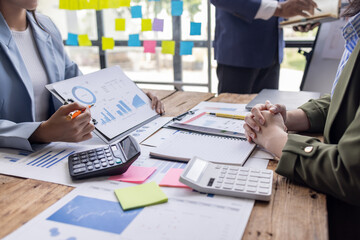 Group of confident business people point to graphs and charts to analyze market data, balance sheet, account, net profit to plan new sales strategies to increase production capacity.	