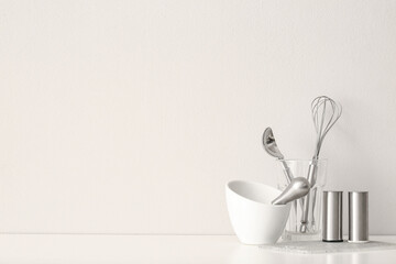 Kitchen utensils on table near white wall