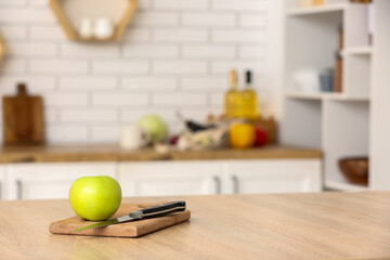 Cutting board with apple and knife on table in kitchen
