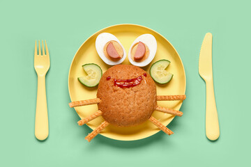 Plate with funny children's breakfast in shape of crab on green background