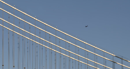 Airplane flies over the Manhattan Bridge, a famous NYC travel landmark in Dumbo, New York City.