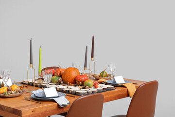 Festive table setting for Thanksgiving day with pumpkins and autumn leaves in dining room