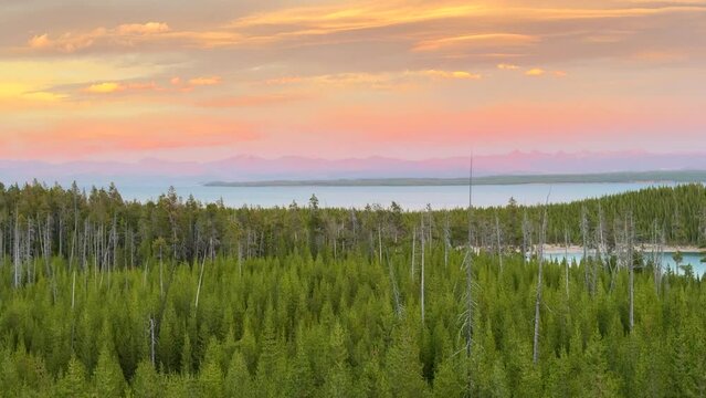 Lake Yellowstone National Park West Thumb Geyser Basin Grant Village stunning late autumn fall peaceful pink orange warm hue sunsets dusk green pines Teton National Forest cinematic pan right slowly