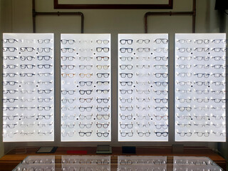 prescription eyeglasses with variety of frames on display on wall