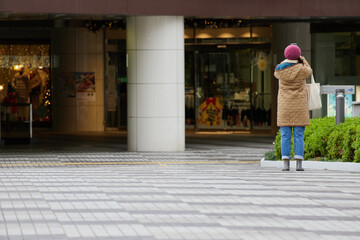 冬の朝の商店街で写真を撮影する中高年女性の姿 - obrazy, fototapety, plakaty