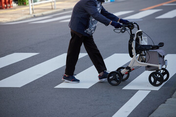 冬の朝の街の横断歩道を渡る一人のシニア女性の姿