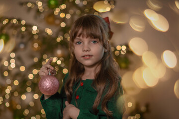 A portrait of a sweet beautiful smiling little 7-old girl wearing green dress, with red bow on the...
