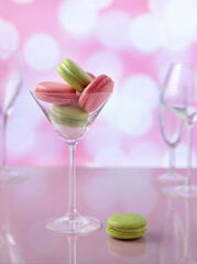 pink and green macarons in clear glass, sweet still life concept. selective focus on macarons in clear glass on pink backgraund