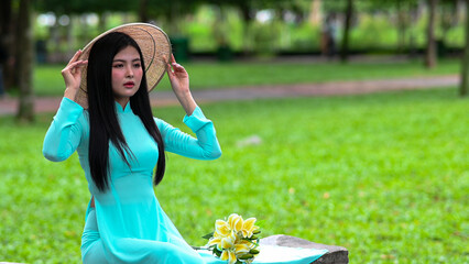 A young girl wearing a jade-green ao dai the traditional costume of Vietnam. Photo for tourism,...