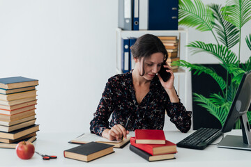 an office worker works in the office on a laptop and talks on the phone