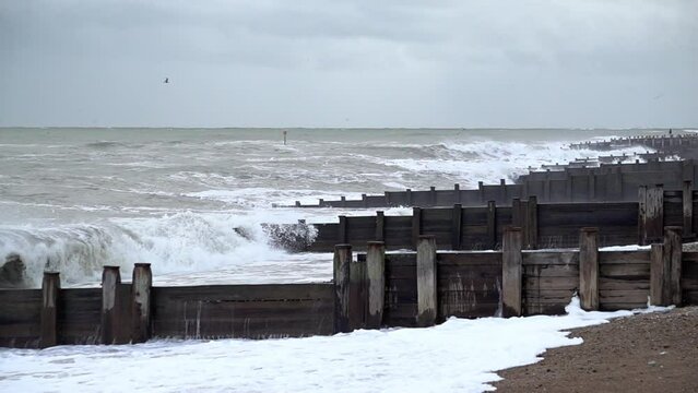 In slow motion large and threatening waves break against groynes on the beach as storm Ciar&aacute;n makes landfall.