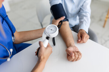 Doctor using sphygmomanometer with stethoscope checking blood pressure to a patient in the hospital.