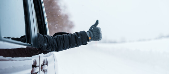 Happy Traveler driving car on snowy road and gesture finger up, man Tourist enjoying snow forest...