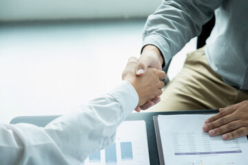 Businessmen giving handshake after working.