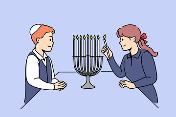 Jewish children stand near minora with burning candles, preparing for traditional holiday hanukkah. Boy in kippah and girl from israel celebrating onset hanukkah, showing commitment to traditions - obrazy, fototapety, plakaty