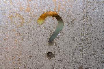 The question mark drawn on a frozen glass window. Frost patterns on window glass with question mark...