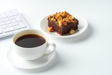 Piece of brownie cake with hazelnuts on white background