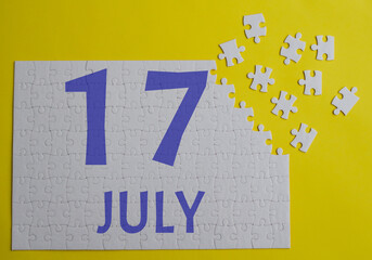 17 july calendar date on a white puzzle with separate details. Puzzle on a yellow background with a blue inscription