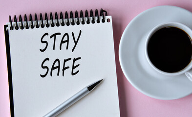 STAY SAFE - words written in a notebook on the background of a cup of coffee and a pen