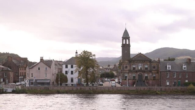 panning shot of church steeple along the river ness with hills in the background in Inverness, Scotland in the Highlands