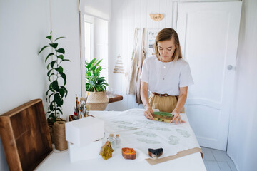 She holds a stamp in her hands for making a design on fabric.