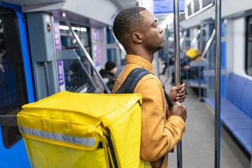 Portrait of an African American male courier with a yellow backpack who goes to pick up an order in...
