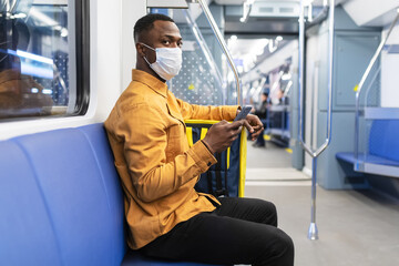 Naklejka na ściany i meble Portrait of a pizza delivery man in a protective mask who rides the subway to deliver an order to a customer during a pandemic
