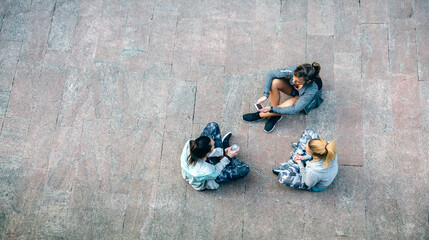 Top view of happy women friends runners relaxing and talking sitting on the floor after urban...