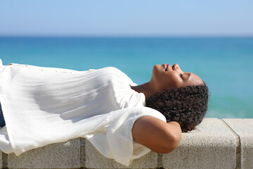 Black woman lying resting on the beach - obrazy, fototapety, plakaty