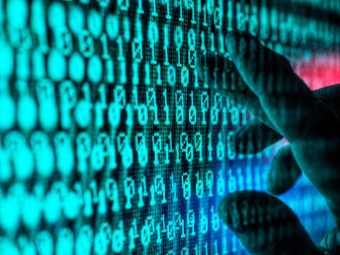 Hand of man touching screen displaying binary code