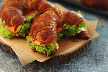 Freshly baked croissants with salmon and salad on the table