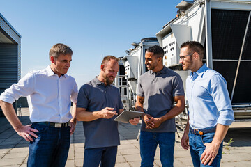 Businessmen and employees having a meeting on rooftop beside refrigeration installation