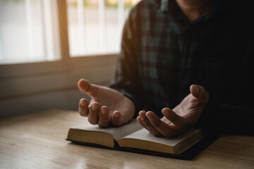Close up of hand. Man doing hands together in prayer to God along with the bible In the Christian...