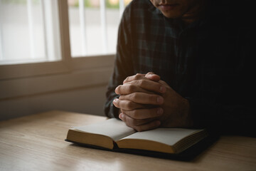Close up of hand. Man doing hands together in prayer to God along with the bible In the Christian concept of faith, spirituality and religion, men pray in the Bible. prayer bible at home. - obrazy, fototapety, plakaty