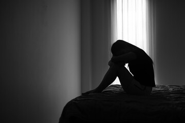 Silhouette of depressed woman sitting in bedroom Beset by health problems accumulated stress Relationship problems.